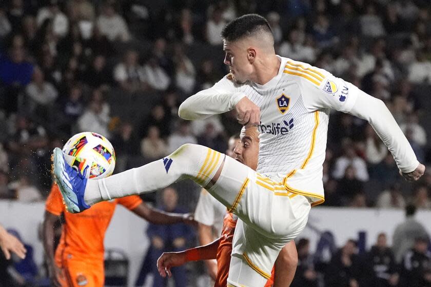 El delantero del LA Galaxy, Gabriel Pec, arriba, patea el balón mientras está bajo presión del Houston Dynamo.