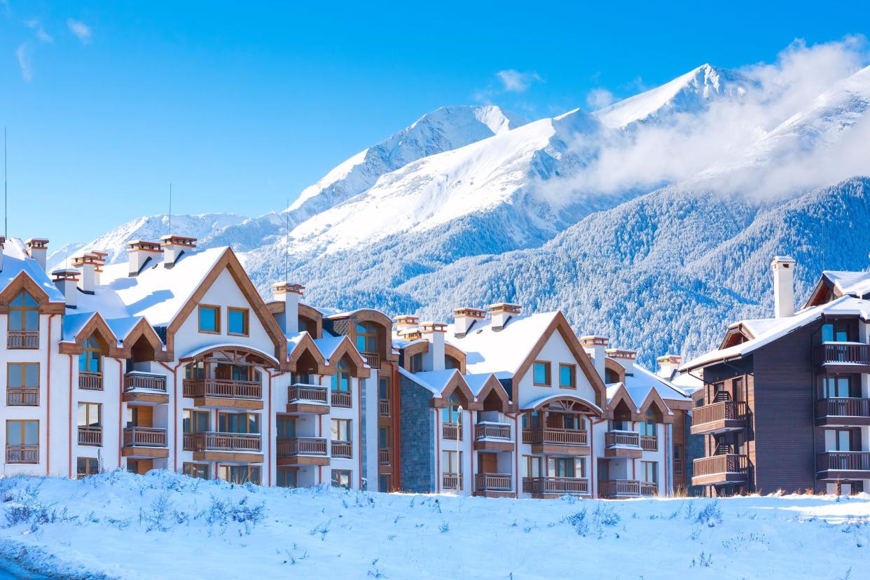 Wooden chalet, houses and snow mountains landscape panorama in bulgarian ski resort Bansko, Bulgaria