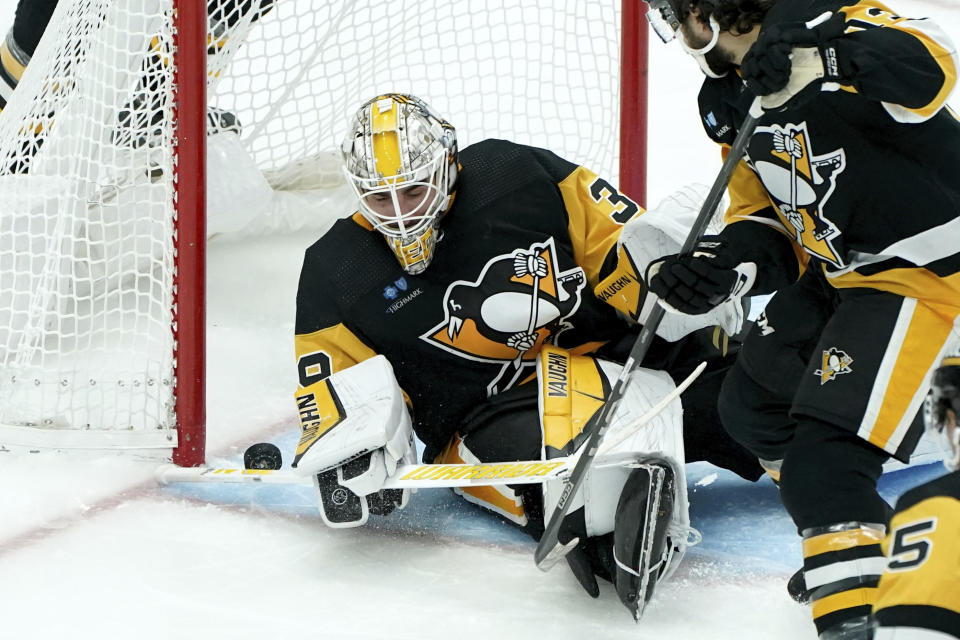 Pittsburgh Penguins goaltender Alex Nedeljkovic, left, reaches to make a save against the New York Islanders during the third period of an NHL hockey game Sunday, Dec. 31, 2023, in Pittsburgh. (AP Photo/Matt Freed)