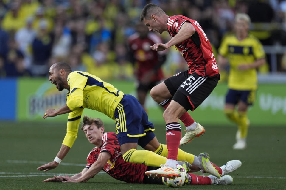 Nashville SC forward Teal Bunbury, center, is tackled by New York Red Bulls midfielder Daniel Edelman, behind and defender Sean Nealis, right, during the first half of an MLS soccer match Sunday, Feb. 25, 2024, in Nashville, Tenn. (AP Photo/George Walker IV)