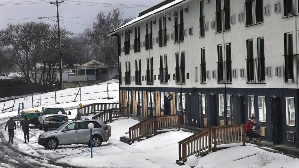 A crew of workers install wood panels over the doors, windows and air conditioning openings Tuesday morning at the former Motel 6 in Kennewick.