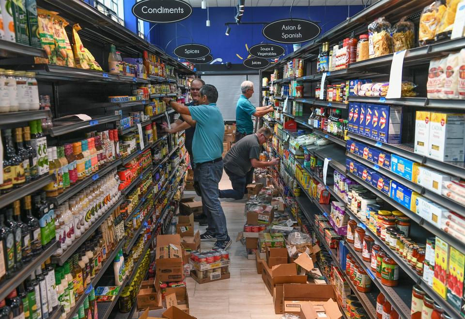 The staff for the new Village Beach Market sock and face the shelves on Friday, July 7, 2023, as they prepare the market in The One Eleven Building  in downtown Fort Pierce for opening day. 