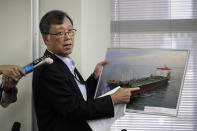 Yutaka Katada, president of Kokuka Sangyo Co., the Japanese company operating one of two oil tankers attacked near the Strait of Hormuz, shows a photo of the attacked oil tanker during a news conference Friday, June 14, 2019, in Tokyo. Iran rejects a U.S. accusation against Tehran over suspected attacks on two oil tankers near the strategic Strait of Hormuz. (AP Photo/Jae C. Hong)