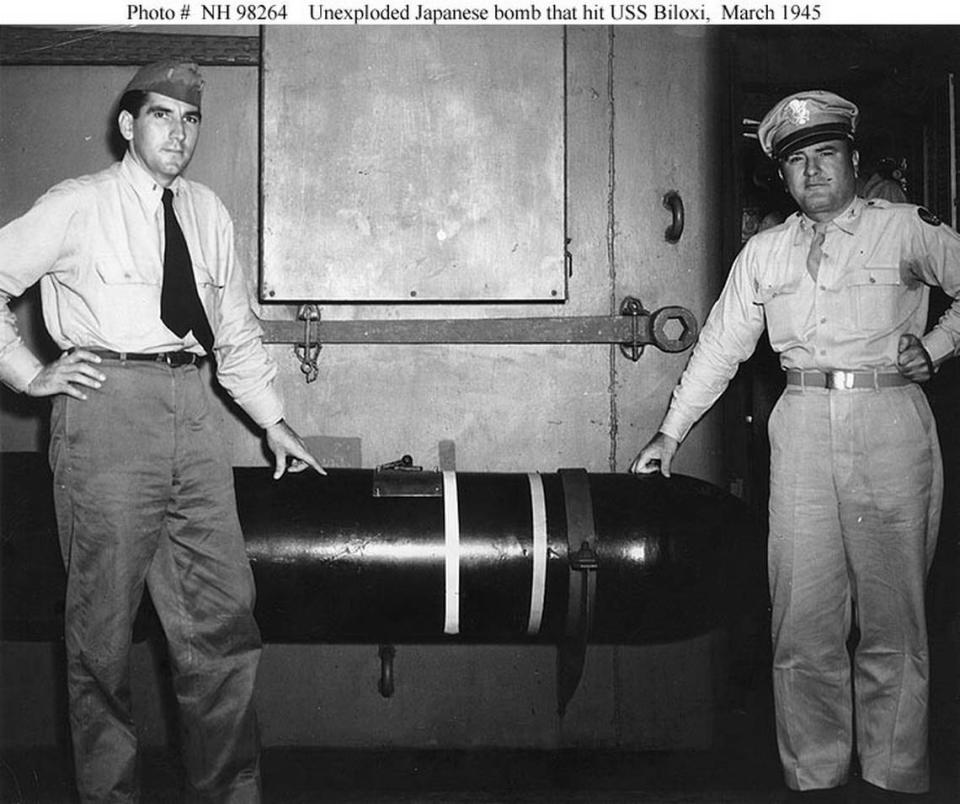 Major Anthony V. Ragusin (right) of Biloxi, Miss., and Ensign Jack Fisher, USNR, of Natchitoches, La. stand next to a 1,000 pound bomb that failed to detonate against the USS Biloxi after a Kamikaze slammed into its side off the coast of Okinawa on March 27, 1945. Naval History and Heritage Command.