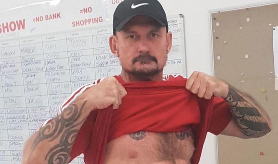 Darwin man Ben Hoffmann is alleged to have carried out a mass shooting which has left four men dead. He is pictured holding up his t-shirt.