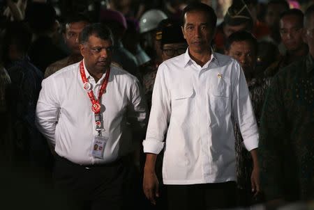 Indonesia's President Joko Widodo (R) walks beside AirAsia's CEO Tony Fernandes after meeting with family members of passengers onboard AirAsia flight QZ8501 in Juanda International Airport, Surabaya December 30, 2014. REUTERS/Beawiharta