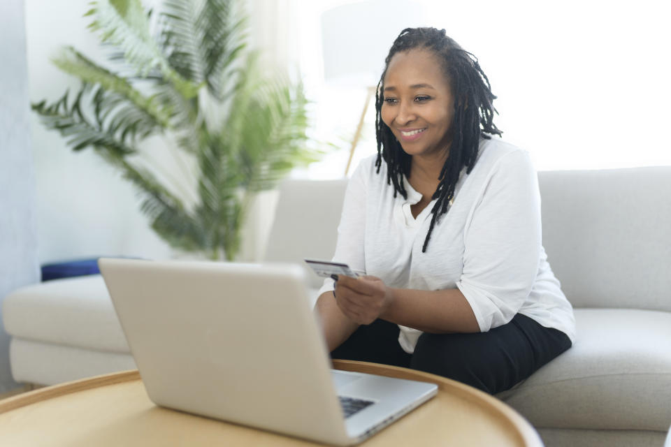 A Photo of pretty black woman using laptop at home sofa and buy something on the web