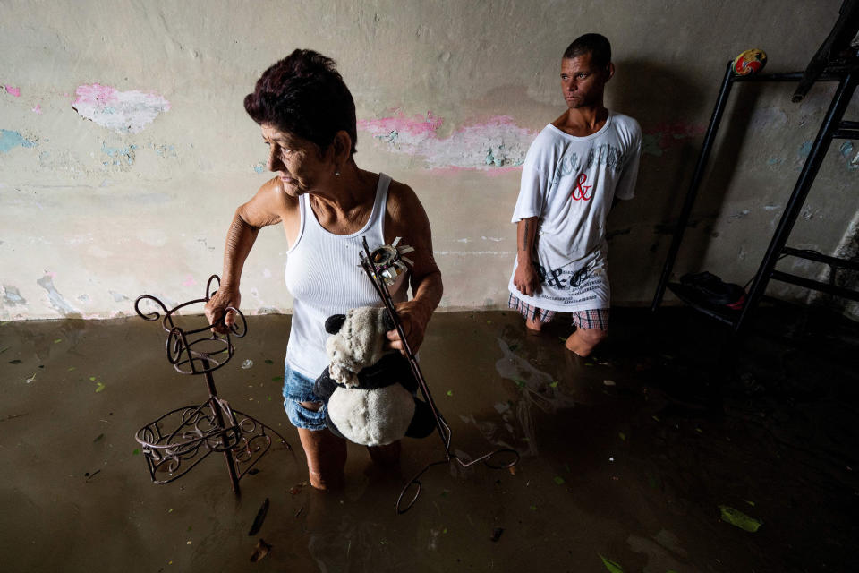 <p>Family members take necessities from their flooded home in Batabano, Cuba, on Sept. 27.</p>