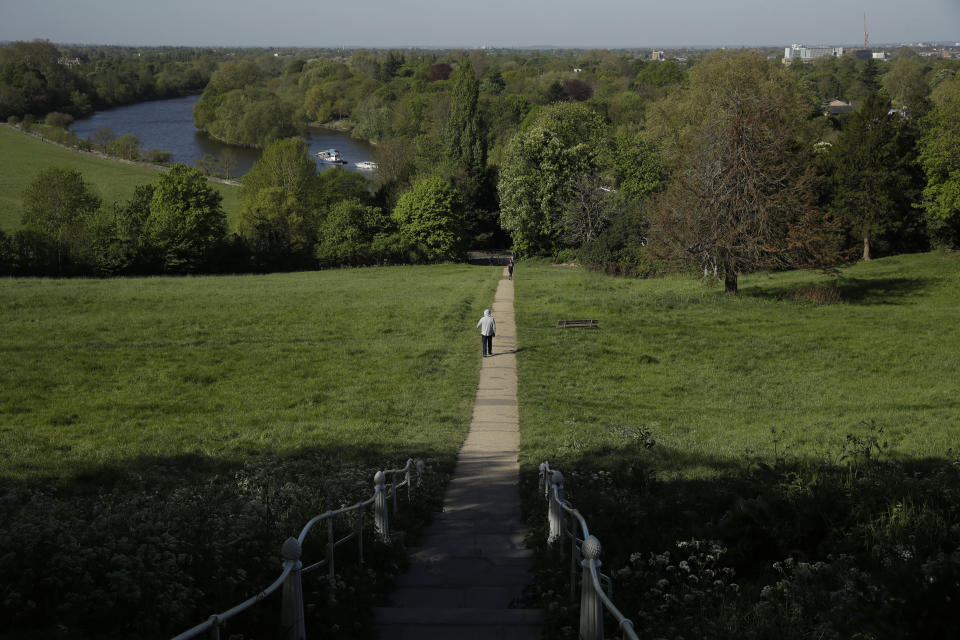 A person walks on a path towards the River Thames in Richmond, London, during the lockdown for the coronavirus, Tuesday, April 21, 2020. The highly contagious COVID-19 coronavirus has impacted on nations around the globe, many imposing self isolation and exercising social distancing when people move from their homes. (AP Photo/Matt Dunham)