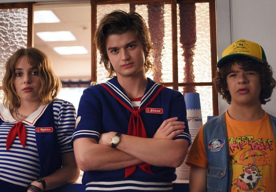 C’est reparti. Alors que le tournage de la saison 4 de « Stranger Things » a débuté comme prévu en mars dernier, celui-ci a rapidement été contraint de s’interrompre quelques jours plus tard, à cause de la crise sanitaire mondiale. Ce n’est qu’au début du mois d’octobre que les acteurs de la série à succès ont pu retrouver le chemin des studios. Ainsi, la semaine dernière, une partie du casting a été aperçue et photographiée dans les rues d’Atlanta, ville dans laquelle le tournage de cette quatrième saison a repris. Dans cette série de clichés, on peut apercevoir Joe Keery (Steve) en compagnie de ses camarades de jeu : Maya Hawke (Robin), Gaten Matarazzo (Dustin) et Sadie Sink (Max). À en croire les images prises sur le tournage, les personnages de Steve et Robin semblent en avoir fini avec le job de vendeur de glaces chez Scoops Ahoy et ont apparemment rendu leur costume de marin pour travailler chez Family Video, une boutique de location de VHS.On remarque également l’arrivée d’une nouvelle recrue parmi la bande de chasseurs de demogorgon : Levon Thurman-Hawke, le fils d’Uma Thurman et Ethan Hawke. Mais pour le moment, nul ne sait si le frère de Maya Hawke à la ville, jouera celui de Robin à l’écran, ou bien un tout autre rôle. Une saison 4 prévue pour 2021 La pandémie de coronavirus a engendré un retard conséquent sur bon nombre de tournages, outre-Atlantique. Ainsi, la quatrième saison de « Stranger Things », initialement prévu pour cette année, ne devrait pas débarquer sur Netflix avant 2021. Pour l’heure, aucune information n’a été révélée concernant la teneur des aventures de Mike, Eleven, Dustin et les autres, mais une certitude demeure : le shérif Hopper, incarné par David Harbour, est bel et bien vivant et serait retenu prisonnier en Russie. Le suspense est donc à son comble pour cette quatrième saison qui ne sera sans doute pas la dernière...