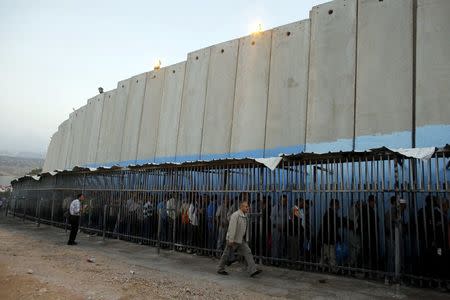 Palestinians wait to cross into Jerusalem next to Israel's controversial barrier at an Israeli checkpoint in the West Bank town of Bethlehem, in this July 7, 2013 file photo. REUTERS/Ammar Awad/Files