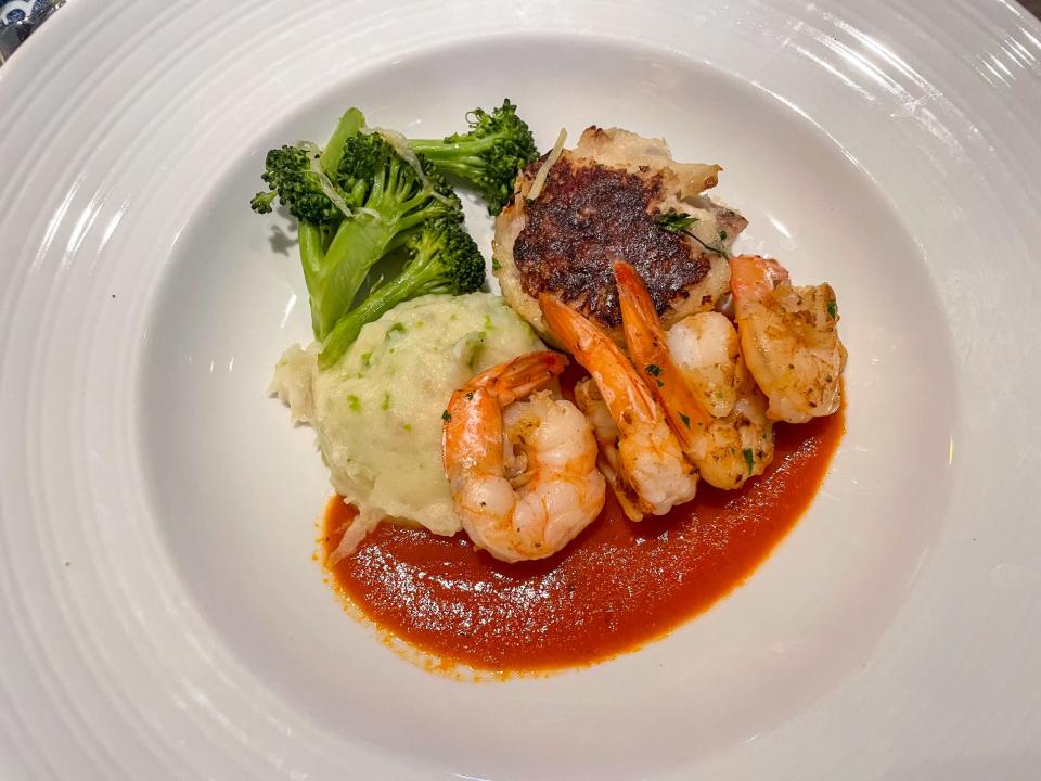 A plate of shrimp, fish cake, vegetables, and tomato sauce.