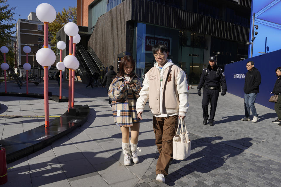 Shoppers walk through a mall district in Beijing, Saturday, Nov. 11, 2023. Shoppers in China have been tightening their purse strings, raising questions over how faltering consumer confidence may affect the annual Singles' Day online retail extravaganza. (AP Photo/Ng Han Guan)