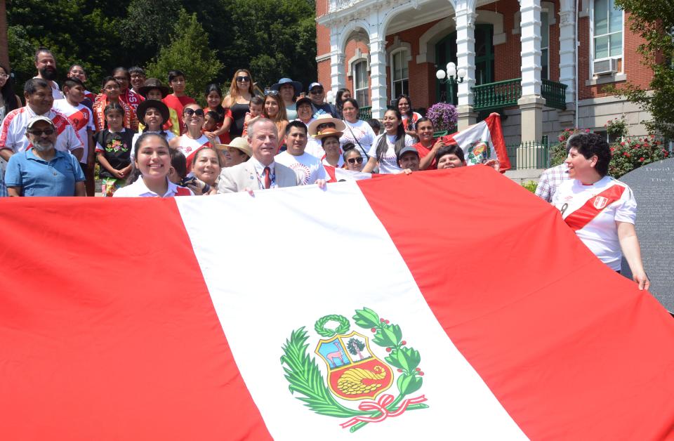 Norwich Mayor Peter Nystrom, center, and some of the more than 100 people attending pose with a Peruvian flag during a bicentennial celebration of the Independence of Peru at City Hall in downtown Norwich last year. Global City Norwich has sponsored many of these flag raisings for different cultures in the city.