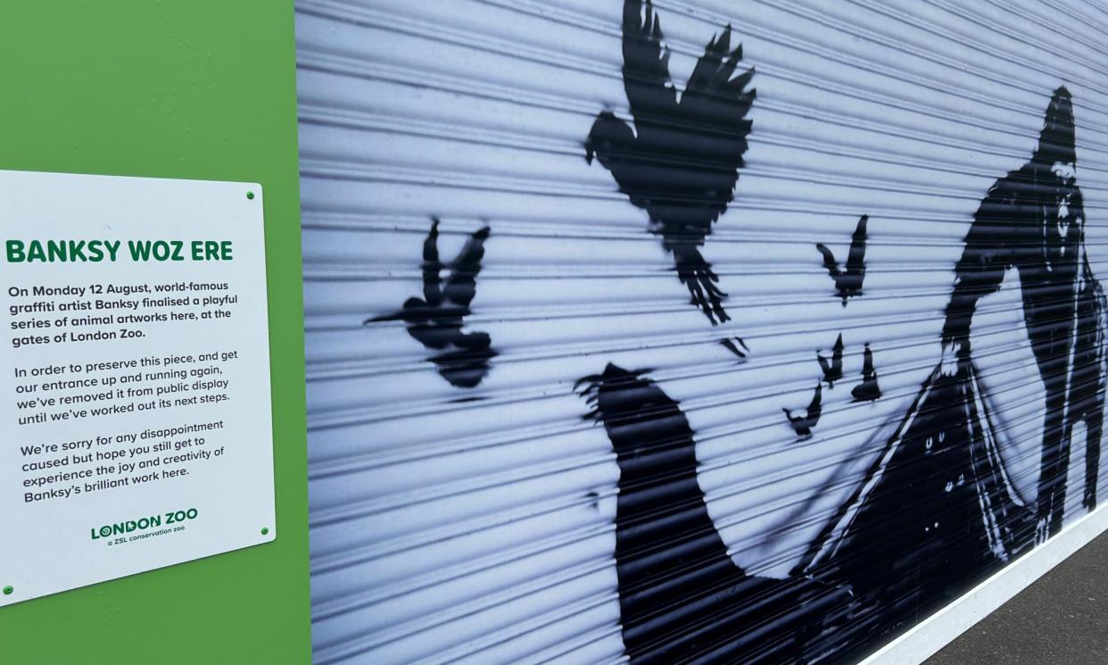 <span>A sign explains why a reproduction has replaced a Banksy mural that was removed on Friday.</span><span>Photograph: Brian Melley/AP</span>