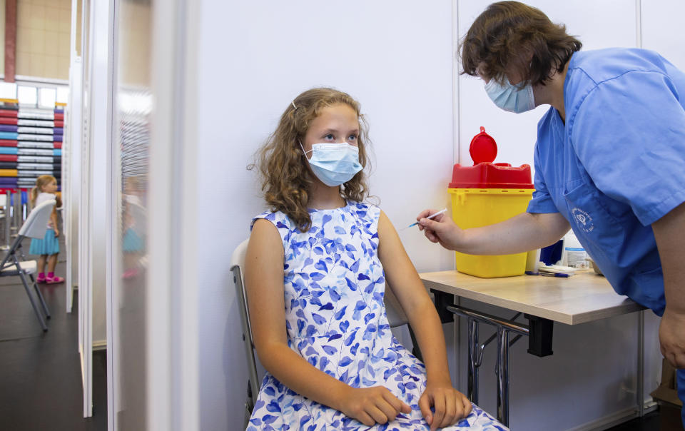 A medical worker, right, administers a shot of a coronavirus vaccine to Gloria Raudjarv, 13-year-old girl, at a vaccination center inside a sports hall in Estonia's second largest city, Tartu, 164 km. south-east from Tallinn, Estonia, Thursday, July 29, 2021. Estonia's second largest city Tartu is making rapid progress in vaccinating children aged 12-17 ahead of the school year in September. Around half of the town's teenagers have already received their first vaccine, and local health officials are confident they will hit 70% in the coming 30 days. (AP Photo/Raul Mee)