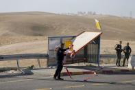 An Israeli policeman removes a cordon at the scene of a Palestinian car ramming attack on two Israeli soldiers near the Jewish settlement of Kfar Adumim, in the occupied West Bank November 27, 2015. REUTERS/Ammar Awad