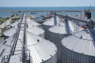 A pilot ship sails behind silos at the Comvex handling and storage facility in the Black Sea port of Constanta, Romania, Tuesday, June 21, 2022. While Romania has vocally embraced the ambitious goal of turning into a main hub for the export of agricultural products from Ukraine, economic experts and port operators in the country warn that it was much easier objective to set than to actually achieve. (AP Photo/Vadim Ghirda)