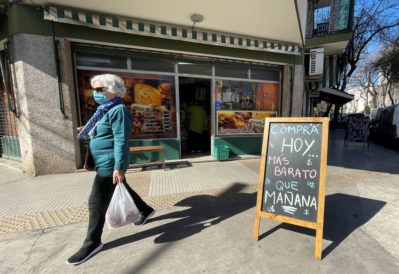 FILE PHOTO: A shopper walks past a placard that reads "Buy today, cheaper than tomorrow", following Argentina's high inflation, as the economic crisis grips, in Buenos Aires