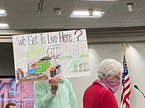 Holland resident Jim Schipper holds a sign opposing UDO, proposed changes to the city of Holland's zoning regulations, while his wife Linda speaks during a city council study session on Wednesday, April 28, 2021, in Holland, Mich.