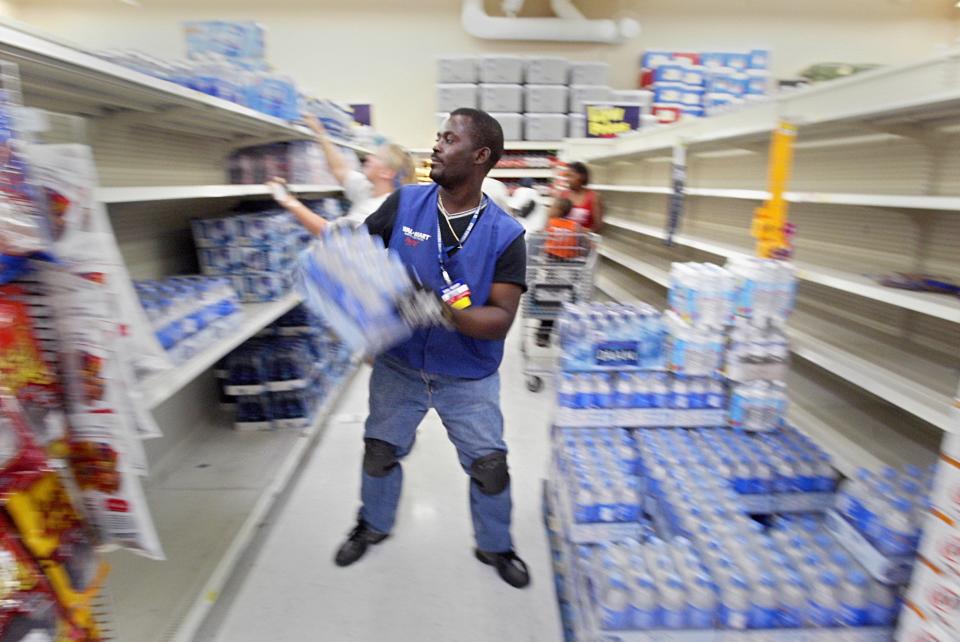 As shoppers prepare for approaching storm Katrina, Walmart Associate Yvon Jules Sainvil works tirelessly to stock shelves with water at the Super Wal-Mart store located at the intersection of Belvedere Road and Military Trail in West Palm Beach August 24, 2005.