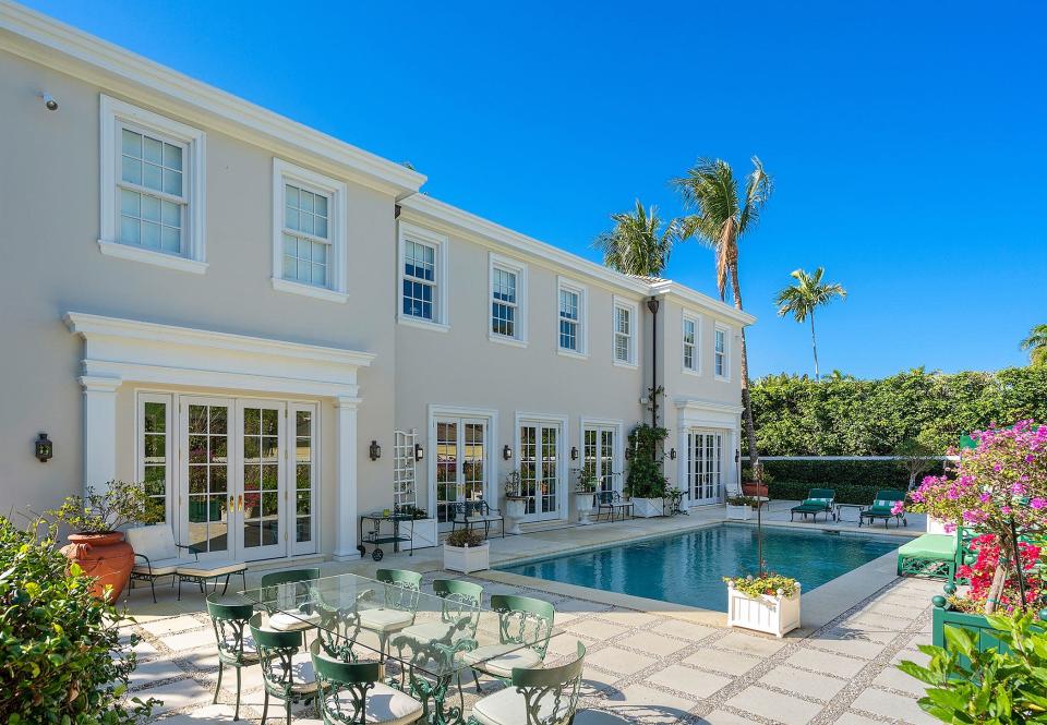 The rear of the house features a symmetrical design, with several sets of French doors opening onto the pool patio.