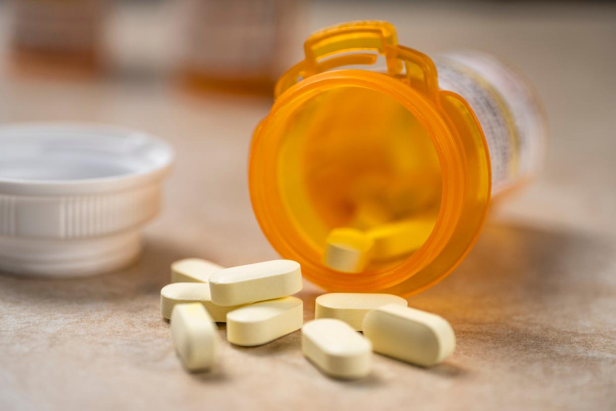 Pills spilling out of prescription bottle - stock photo