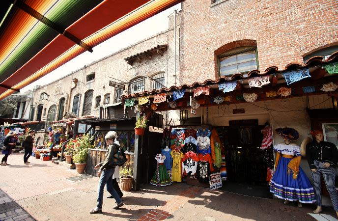 FILE --In this March 3, 2011 file photo, tourists shop at Olvera Street stores at El Pueblo de Los Angeles Historic District in Los Angeles. The area to visit for the cool free stuff, though, is on the north side of the Hollywood Freeway, home to the historic El Pueblo de Los Angeles, where the city was founded in 1781. There you'll see many of its oldest and most beautiful buildings restored to their previous grandeur. (AP Photo/Damian Dovarganes,File)