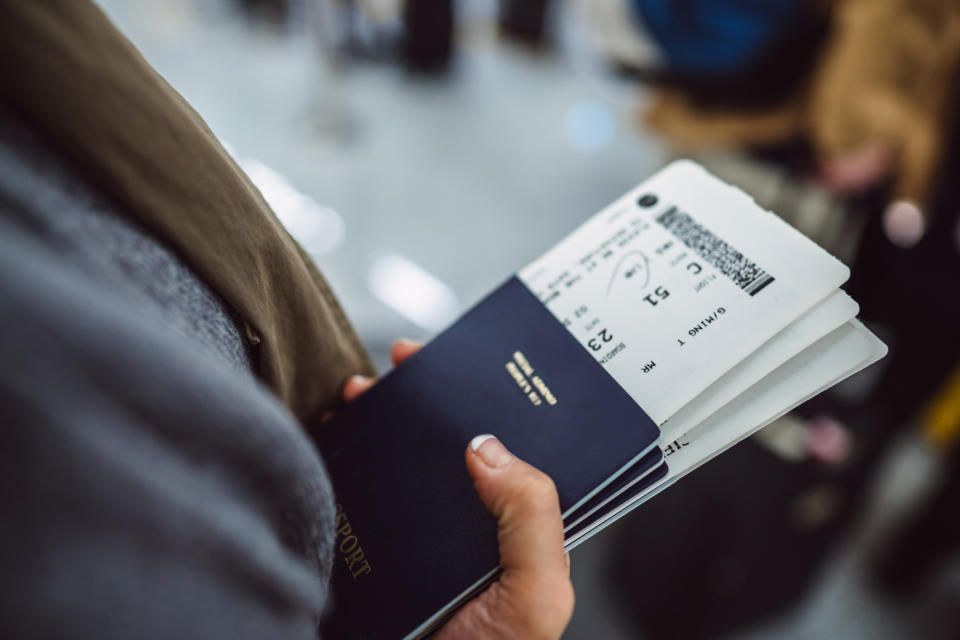 Woman’s hands holding passports & boarding passes.