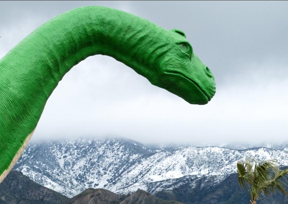 A Jurassic scene in Cabazon as snow covers the nearby mountains.