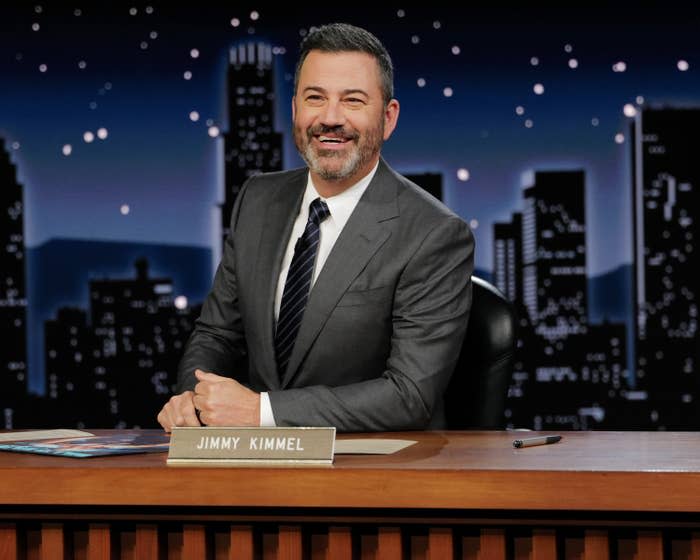 Close-up of Jimmy Kimmel smiling at his desk on his talk show