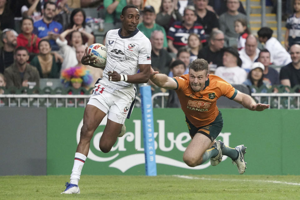 FILE - Perry Baker of the United States runs to score a try as he breaks away from Australia's Hayden Sargeant during the second day of the Hong Kong Sevens rugby tournament in Hong Kong, Saturday, April 1, 2023. The US hasn't won an Olympic medal in rugby sevens since the sport was introduced in 2016. (AP Photo/Anthony Kwan, File)