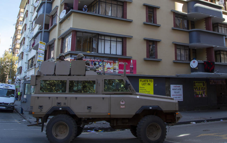 Residents stand on a balcony as a South African National Defence Forces vehicle patrol the street, in Johannesburg, South Africa, Tuesday, April 7, 2020. South Africa and more than half of Africa's 54 countries have imposed lockdowns, curfews, travel bans or other restrictions to try to contain the spread of COVID-19. The new coronavirus causes mild or moderate symptoms for most people, but for some, especially older adults and people with existing health problems, it can cause more severe illness or death. (AP Photo/Themba Hadebe)