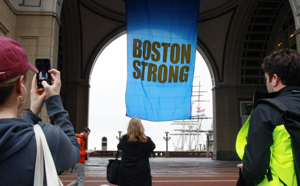 People photograph a banner reading "Boston Strong" as it hangs at Rowes Wharf on the first anniversary of the Boston Marathon bombings, Tuesday, April 15, 2014, in Boston. (AP Photo/Bill Sikes)