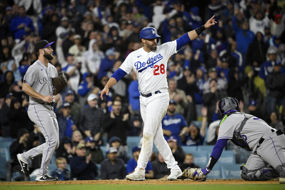 Los Angeles Dodgers' J.D. Martinez, center, celebrates after scoring on a triple by James Outman as Colorado Rockies relief pitcher Jake Bird, left, and catcher Elias Diaz stand by during the fifth inning of a baseball game Monday, April 3, 2023, in Los Angeles. (AP Photo/Mark J. Terrill)