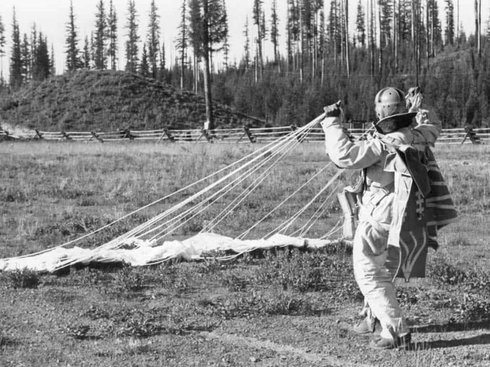 Smoke jumper on ground reels in his parachute