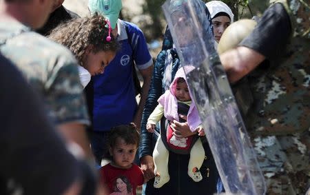 Women and children standing at the Greek side of the border wait with other migrants to cross into Macedonia, near Gevgelija August 24, 2015. REUTERS/Ognen Teofilovski