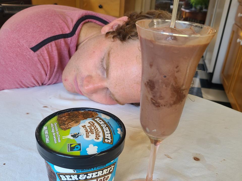 Clayon sleeping on the table behind the carton and serving of ice cream