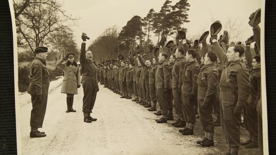 Gerald Bullock leads the West Nova Scotia Regiment through a rousing rendition of Three Cheers for His Majesty on Jan. 24, 1940, in England, during a troop inspection. King George VI is to Bullock's left, saluting.