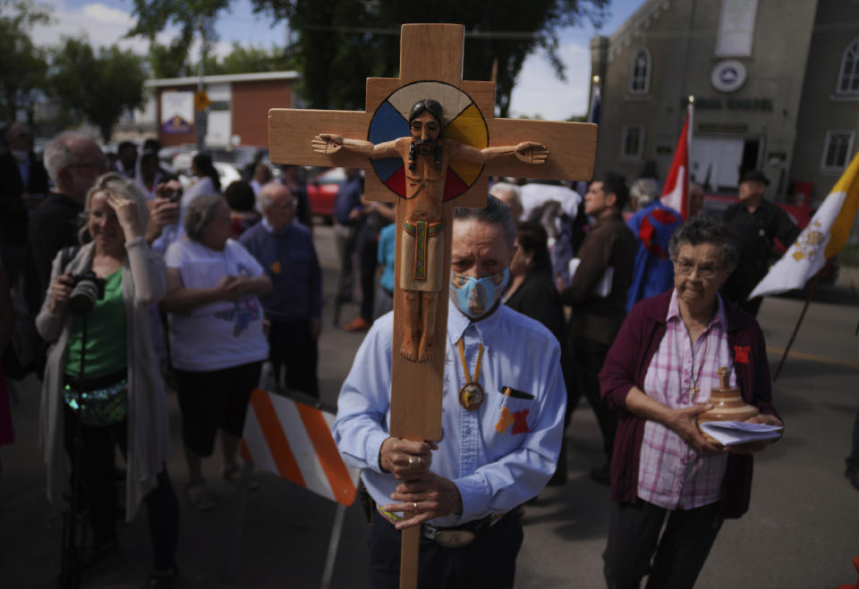 Elmer Waniandy raises the crucifix as he leads his fellow parishioner into the rededicated and newly renovated Sacred Heart Church of the First Peoples sanctuary, on Sunday, July 17, 2022, in Edmonton, Alberta. Pope Francis will meet with parishioners at Sacred Heart during his visit to the Canadian province. (AP Photo/Jessie Wardarski)