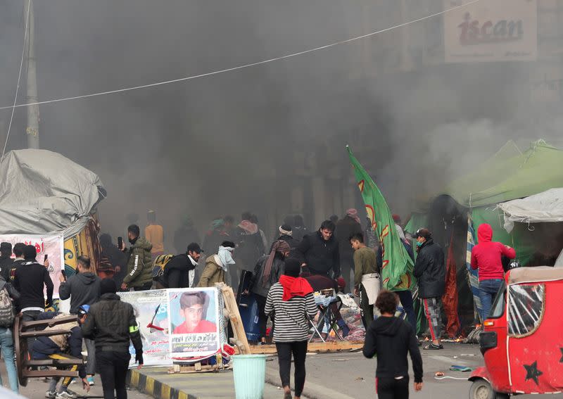 Demonstratos are seen amongst smoke rising from burning tents as Iraqi security forces raid at Tahrir Square during ongoing anti-government protests in Baghdad