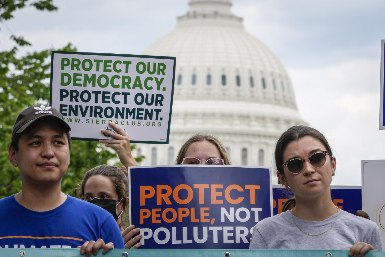 Environmental activists rally near the Capitol, holding signs that read: Protect people, not polluters.