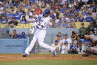Los Angeles Dodgers' Cody Bellinger, left hits a two-run home run as Arizona Diamondbacks catcher Bryan Holaday watches during the first inning of a baseball game Saturday, July 10, 2021, in Los Angeles. (AP Photo/Mark J. Terrill)