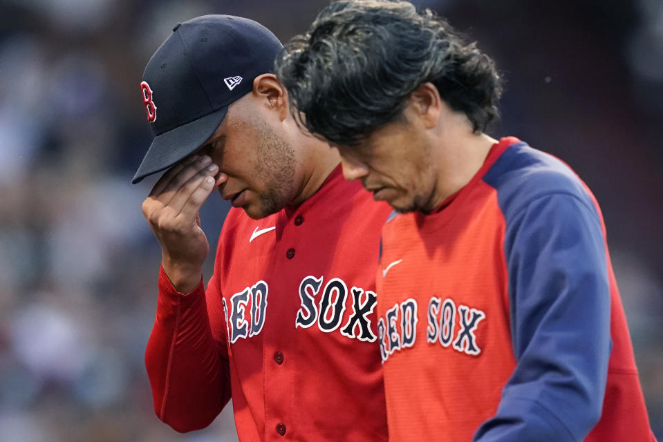 Boston Red Sox starting pitcher Eduardo Rodriguez, left, leaves the baseball game with an injury, accompanied by team trainer Masai Takahashi during the second inning of the team's game against the New York Yankees at Fenway Park, Friday, July 23, 2021, in Boston. (AP Photo/Elise Amendola)