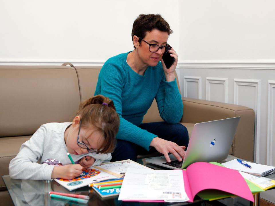 A mother working from home as her child works next to her