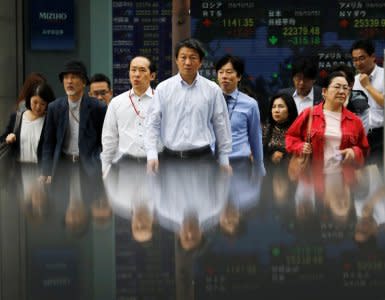 People walk in front of an electronic stock quotation board outside a brokerage in Tokyo, Japan, October 15, 2018.   REUTERS/Toru Hanai