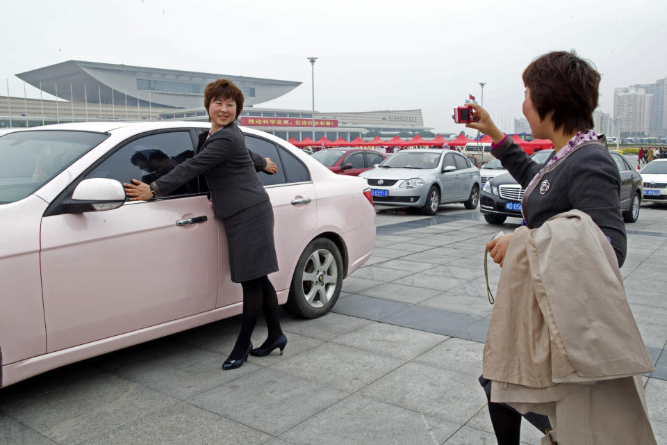 Salespersons pose for pictures in front of a pink sedan, an award for the best sales team, during the Mary Kay China Leadership Conference on February 20, 2011, in China. (Photo by China Photos/Getty Images)