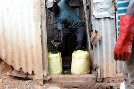 A Kenyan 'frogger' slum dweller Godffrey Ndalo uses a broken plastic jerrycan to empty excrement from a pit latrine in Kibera slum within Nairobi, Kenya February 24, 2019. REUTERS/Njeri Mwangi