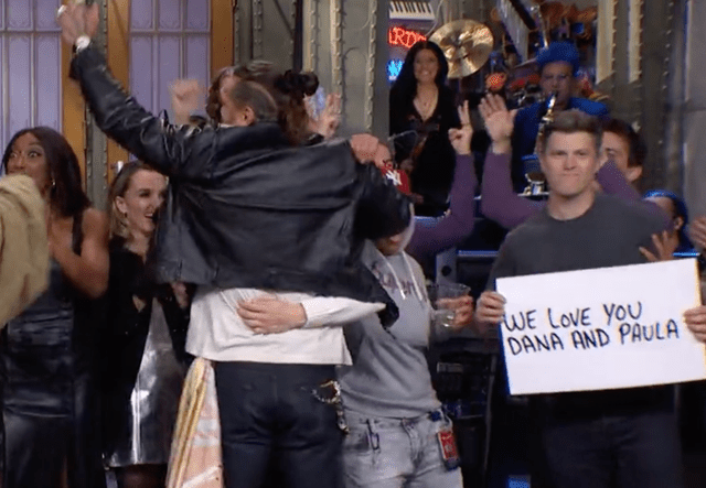 Colin Jost holds sign for Dana Carvey on 'SNL.'