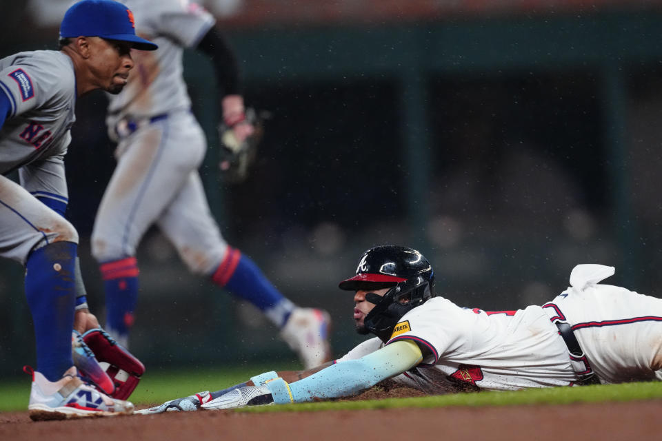 Atlanta Braves' Ronald Acuña Jr. steals second base as New York Mets shortstop Francisco Lindor (12) handles the late throw in the fourth inning of a baseball game Tuesday, April 9, 2024, in Atlanta. (AP Photo/John Bazemore)